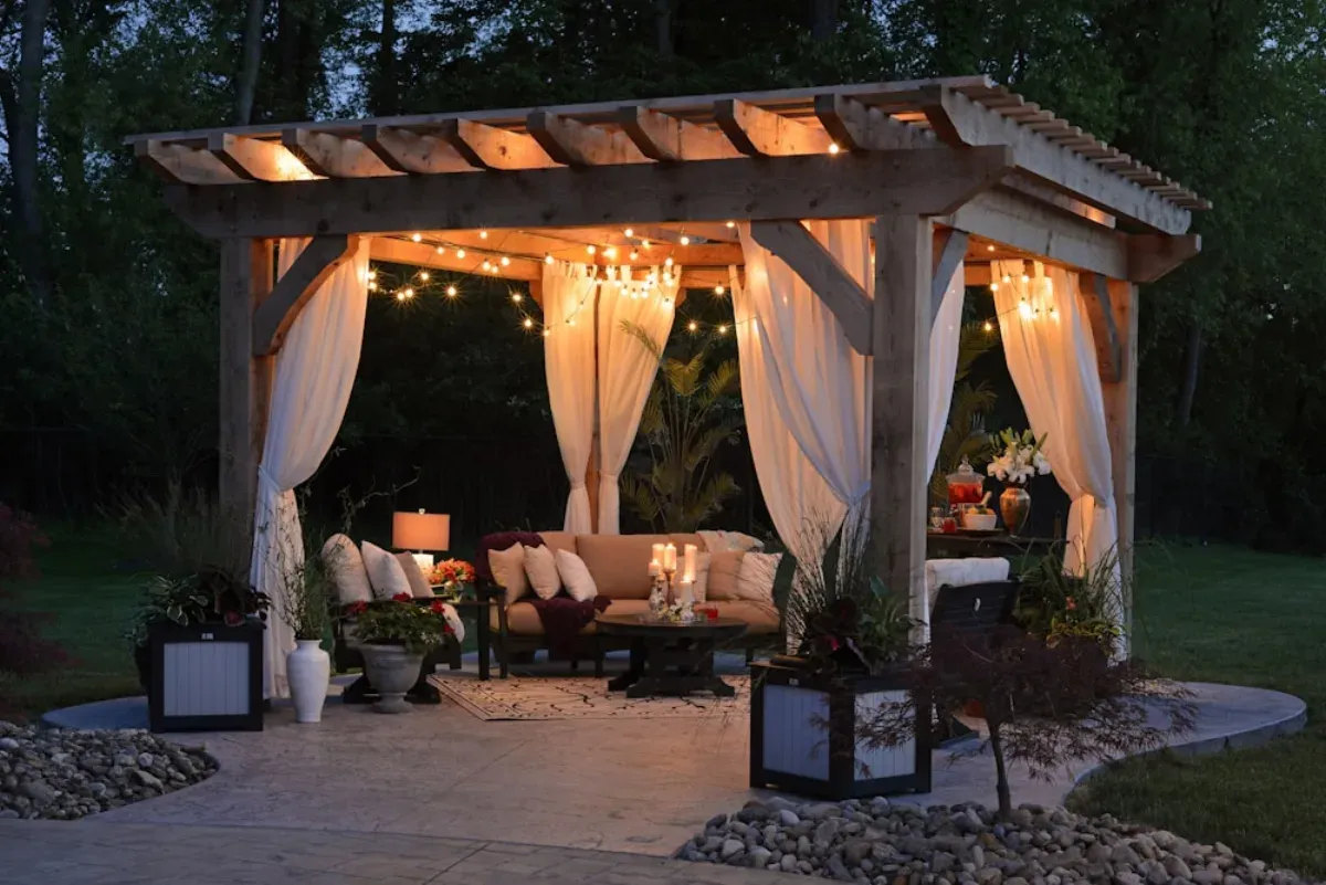 Elegant pergola with string lights and curtains creating an intimate outdoor living space at dusk
